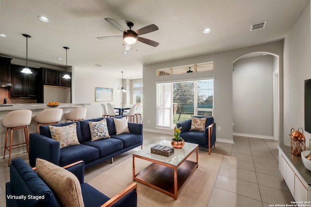 tiled living room featuring ceiling fan and a textured ceiling