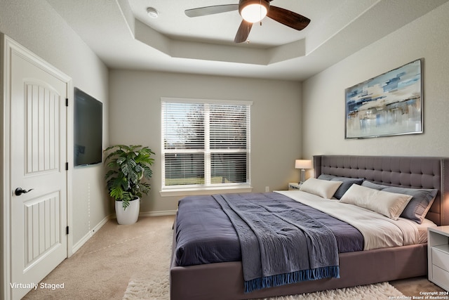 carpeted bedroom with a tray ceiling and ceiling fan