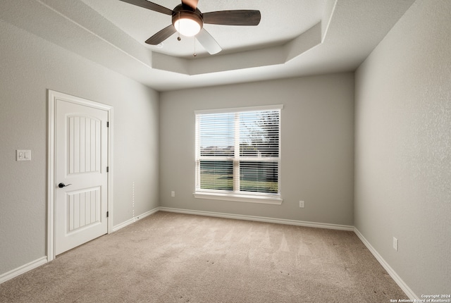 spare room with light carpet, a raised ceiling, and ceiling fan