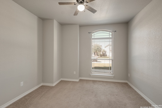 unfurnished room featuring ceiling fan, light colored carpet, and a textured ceiling