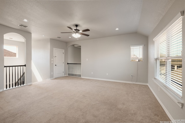 spare room featuring a textured ceiling, ceiling fan, light colored carpet, and lofted ceiling