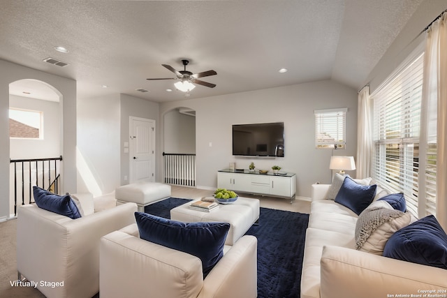 carpeted living room with ceiling fan, lofted ceiling, and a textured ceiling