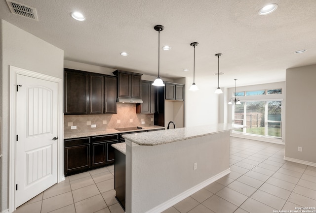 kitchen with a center island with sink, decorative light fixtures, light tile patterned floors, and backsplash