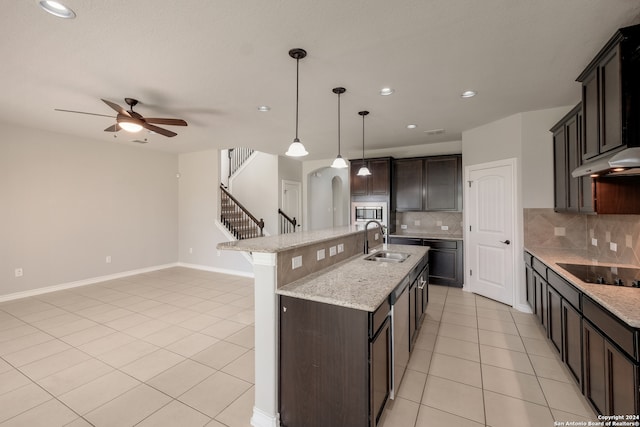 kitchen featuring sink, tasteful backsplash, pendant lighting, black electric cooktop, and a center island with sink