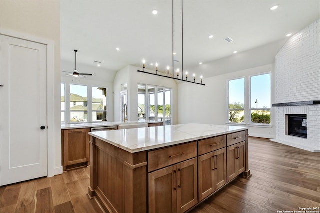 334 Dulce Vis, Boerne, TX 78006 - kitchen featuring a sink, open floor plan, a kitchen island, wood finished floors, and a brick fireplace
