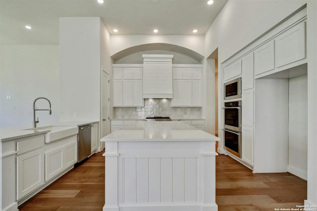 kitchen with a kitchen island, decorative backsplash, sink, stainless steel appliances, and white cabinets