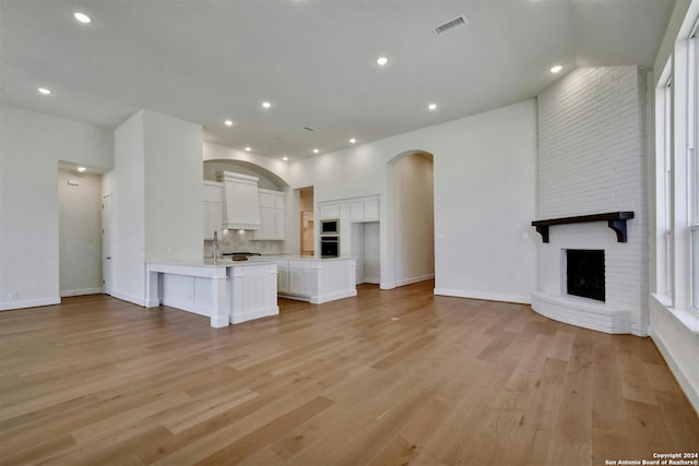 unfurnished living room with a brick fireplace and light hardwood / wood-style floors