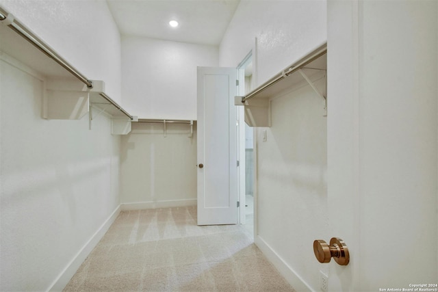 walk in closet with light colored carpet