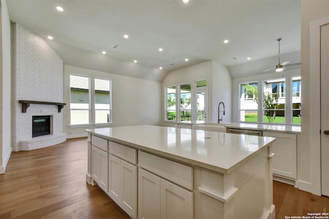 kitchen featuring vaulted ceiling, a fireplace, white cabinetry, and a kitchen island