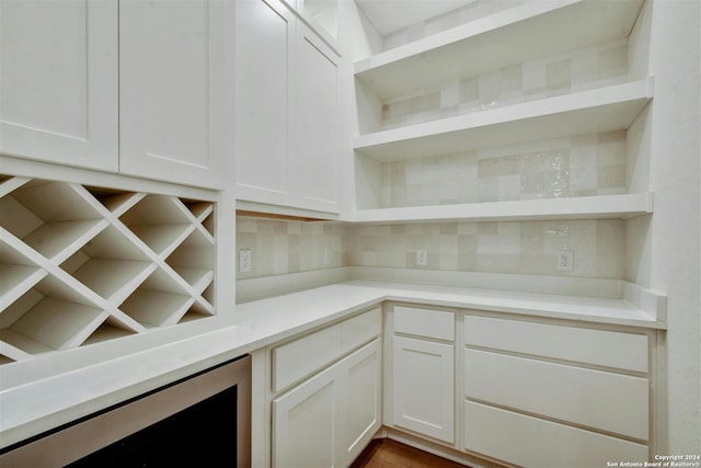 interior space featuring decorative backsplash, wine cooler, and white cabinets