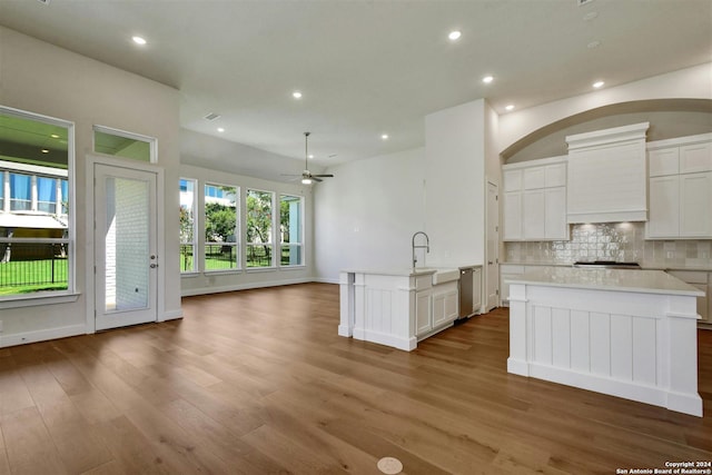 kitchen with ceiling fan, white cabinetry, decorative backsplash, and a kitchen island with sink