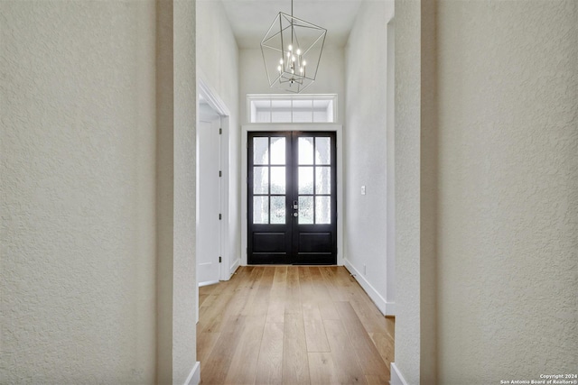 entrance foyer with a chandelier, light hardwood / wood-style flooring, and french doors