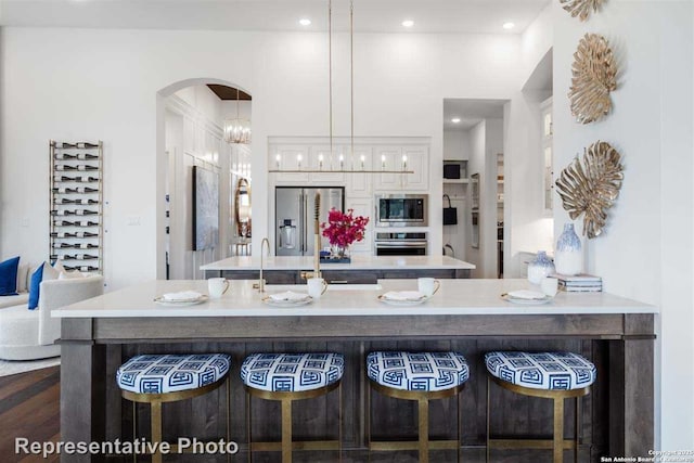 kitchen featuring decorative light fixtures, white cabinetry, stainless steel appliances, and a breakfast bar area