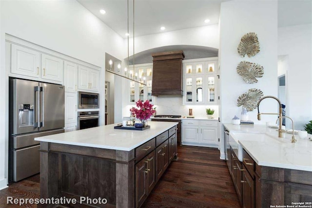 kitchen featuring stainless steel appliances, custom exhaust hood, white cabinetry, and pendant lighting