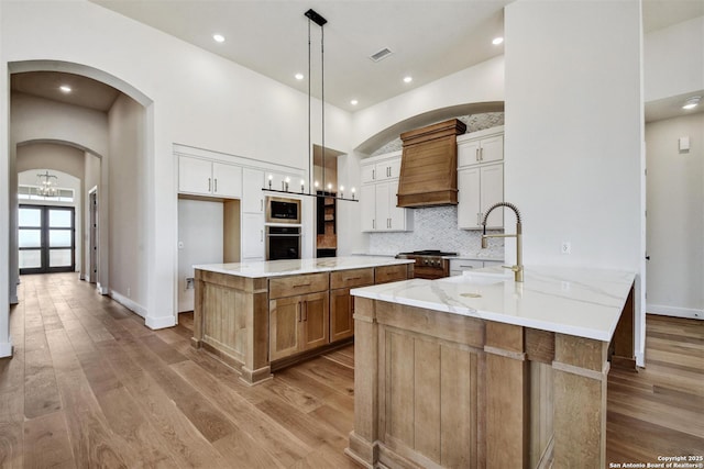 334 Dulce Vis, Boerne, TX 78006 - kitchen with wall oven, custom range hood, a sink, a chandelier, and arched walkways