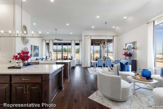 kitchen with ceiling fan with notable chandelier, pendant lighting, lofted ceiling, sink, and dark hardwood / wood-style floors