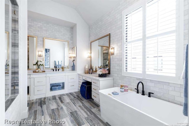 bathroom with vaulted ceiling, hardwood / wood-style floors, a washtub, and vanity