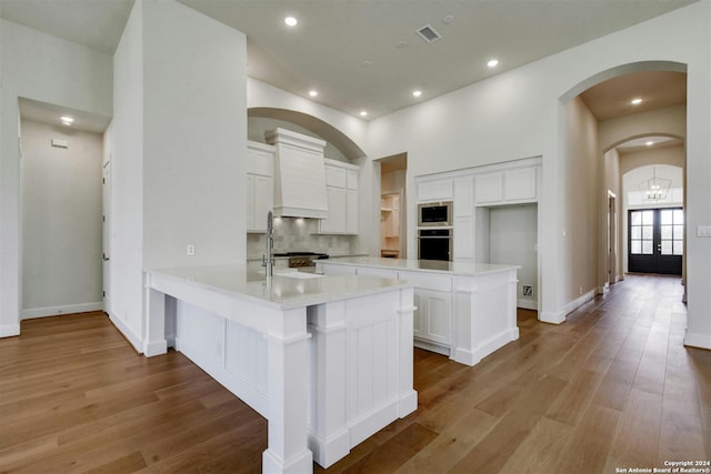 kitchen with a kitchen island, white cabinetry, stainless steel appliances, french doors, and kitchen peninsula