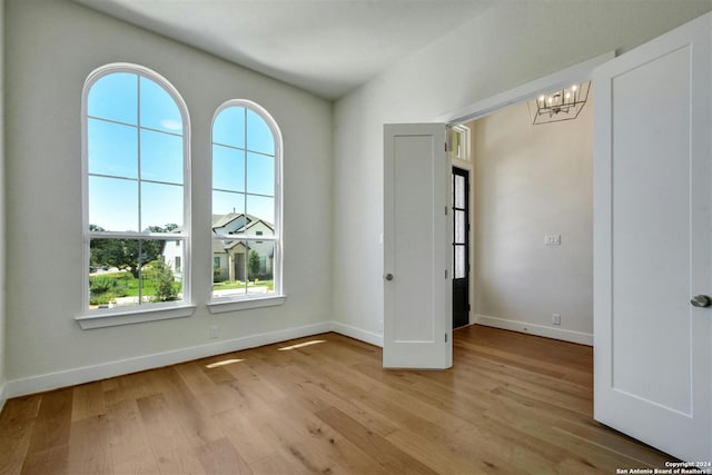 empty room featuring light hardwood / wood-style floors and a notable chandelier