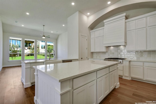 kitchen featuring custom exhaust hood, kitchen peninsula, a center island, vaulted ceiling, and sink