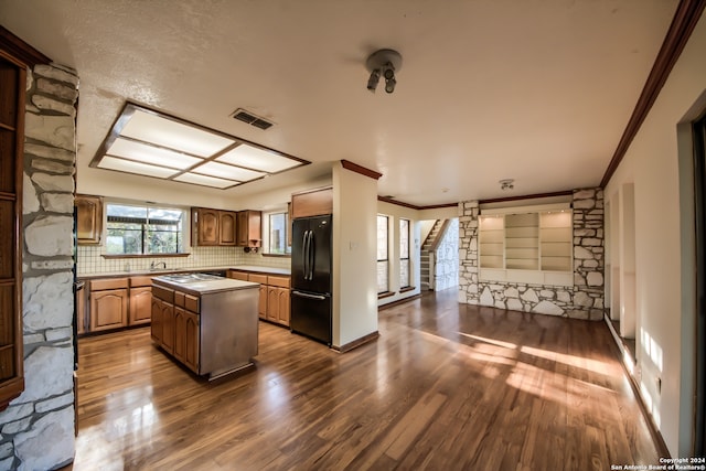 kitchen featuring a center island, black refrigerator, sink, crown molding, and dark hardwood / wood-style floors