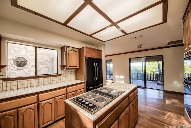 kitchen featuring dark hardwood / wood-style flooring, tasteful backsplash, black appliances, tile countertops, and a kitchen island