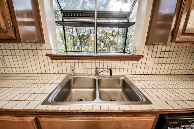 details with decorative backsplash, tile countertops, and sink