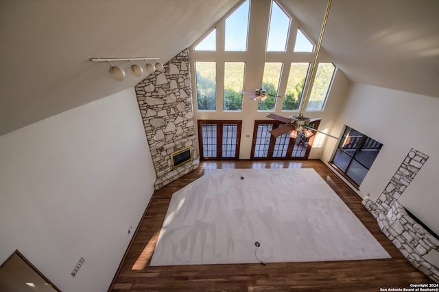 living room featuring high vaulted ceiling, a stone fireplace, ceiling fan, dark hardwood / wood-style flooring, and heating unit