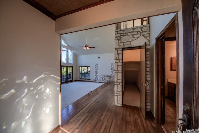 hallway with hardwood / wood-style flooring, high vaulted ceiling, and ornamental molding