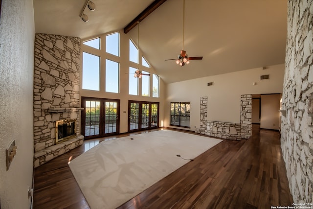 unfurnished living room with high vaulted ceiling, french doors, a stone fireplace, ceiling fan, and dark hardwood / wood-style floors