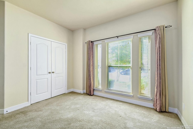 unfurnished bedroom featuring light carpet and a closet