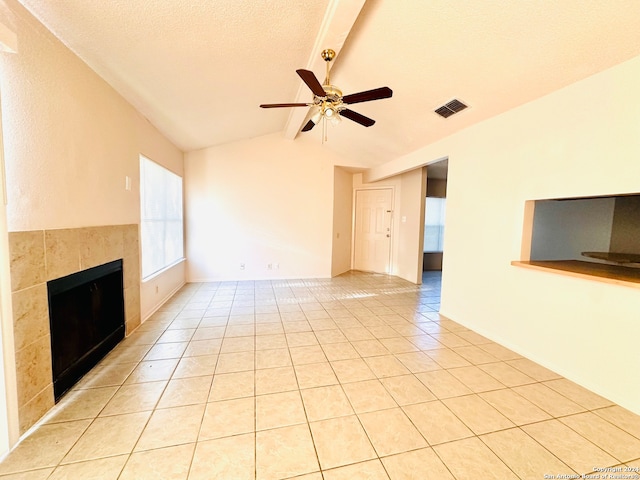 unfurnished living room with lofted ceiling with beams, ceiling fan, light tile patterned floors, a textured ceiling, and a fireplace