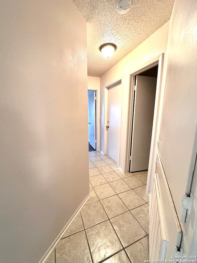 hallway featuring light tile patterned floors and a textured ceiling