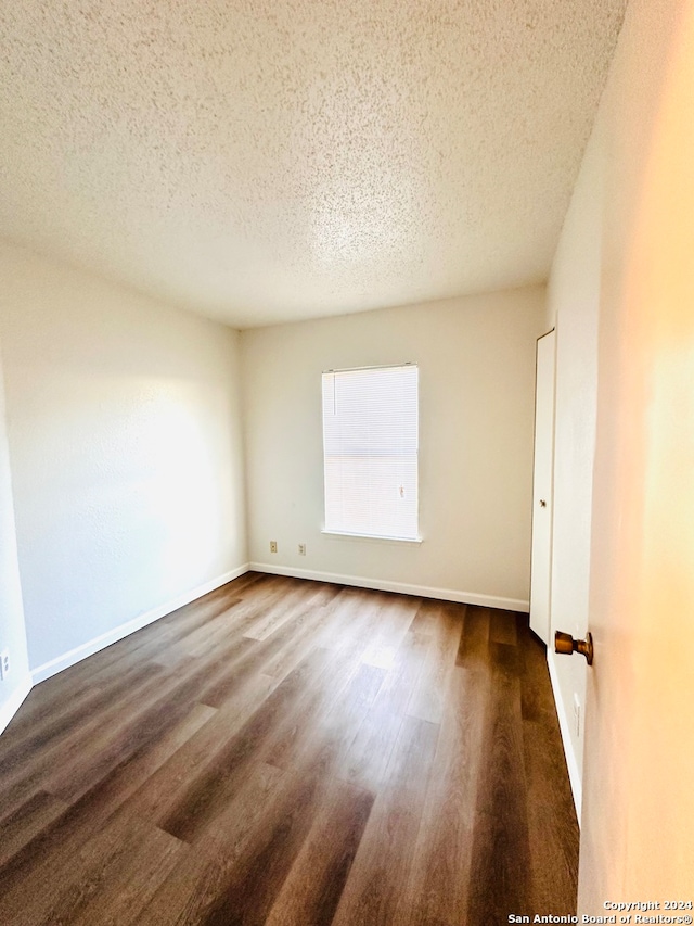 spare room with dark hardwood / wood-style flooring and a textured ceiling