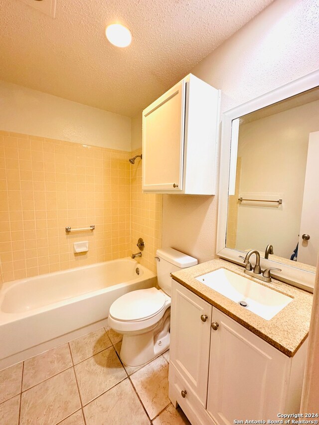 full bathroom with tile patterned flooring, a textured ceiling, vanity, and toilet