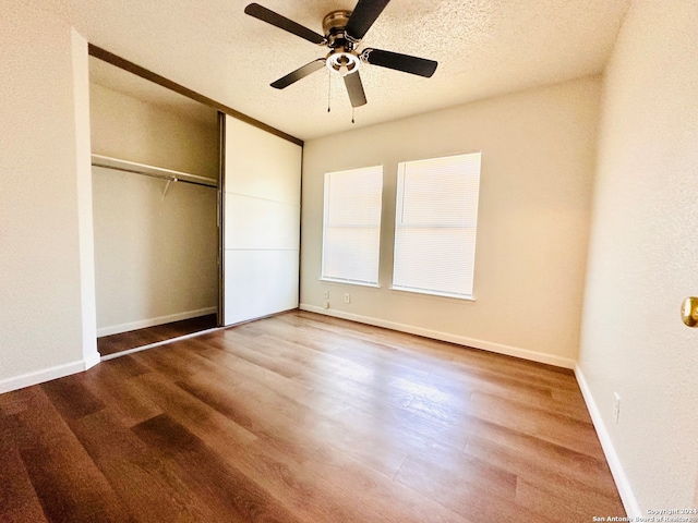 unfurnished bedroom with ceiling fan, a closet, wood-type flooring, and a textured ceiling