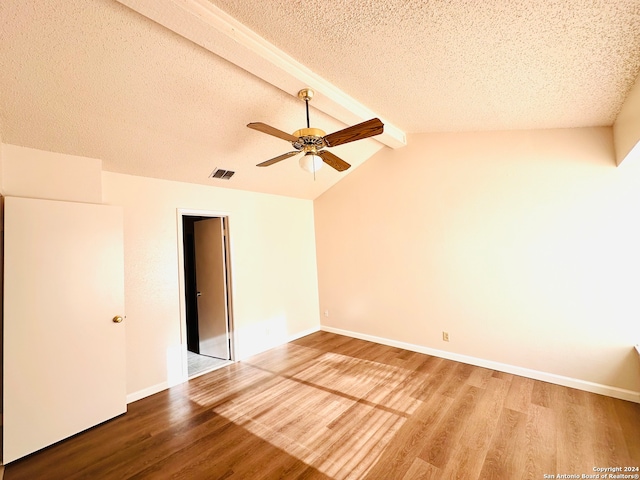 spare room with lofted ceiling, ceiling fan, wood-type flooring, and a textured ceiling