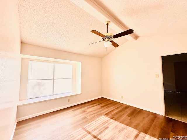 spare room featuring a textured ceiling, lofted ceiling with beams, hardwood / wood-style flooring, and ceiling fan