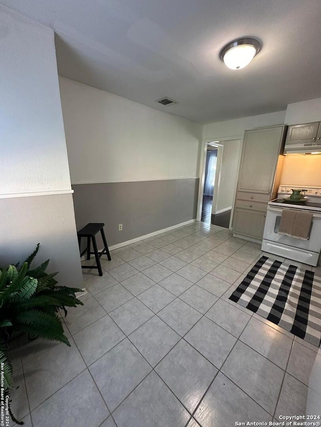 interior space with gray cabinetry, light tile patterned flooring, and white electric stove