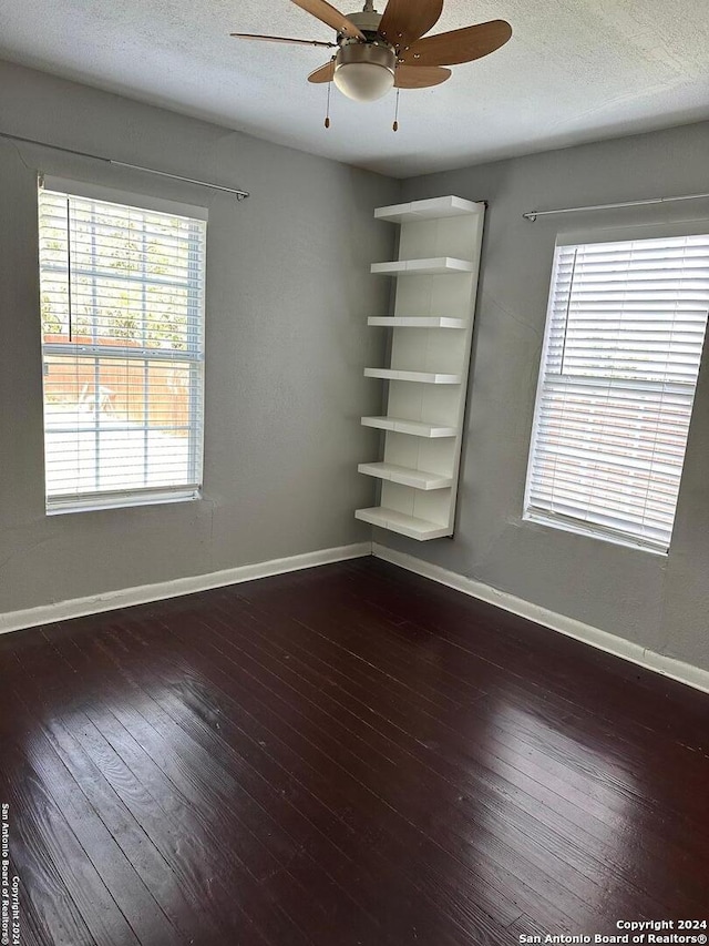 empty room with a textured ceiling, dark hardwood / wood-style flooring, and ceiling fan