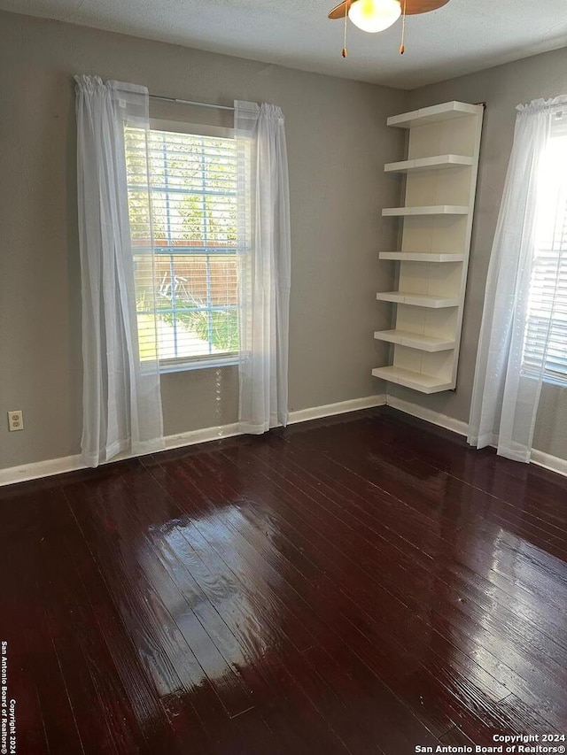 spare room featuring a textured ceiling, ceiling fan, and dark wood-type flooring