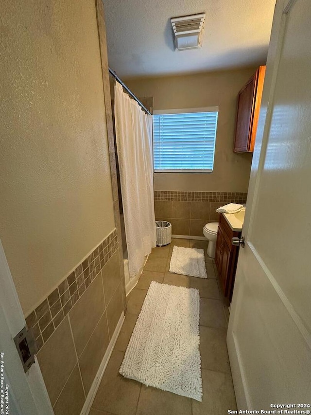 bathroom featuring tile patterned flooring, vanity, and tile walls