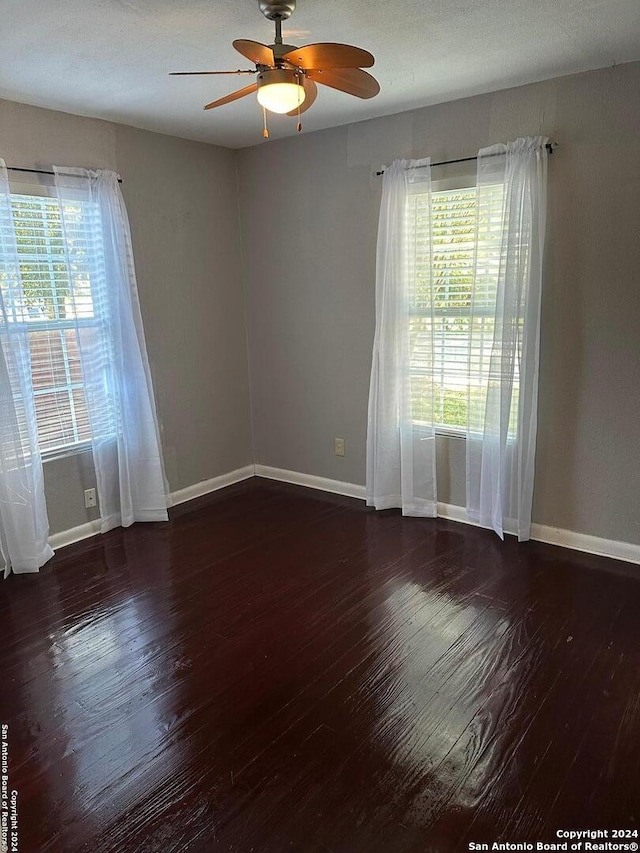 unfurnished room with plenty of natural light, dark wood-type flooring, and ceiling fan