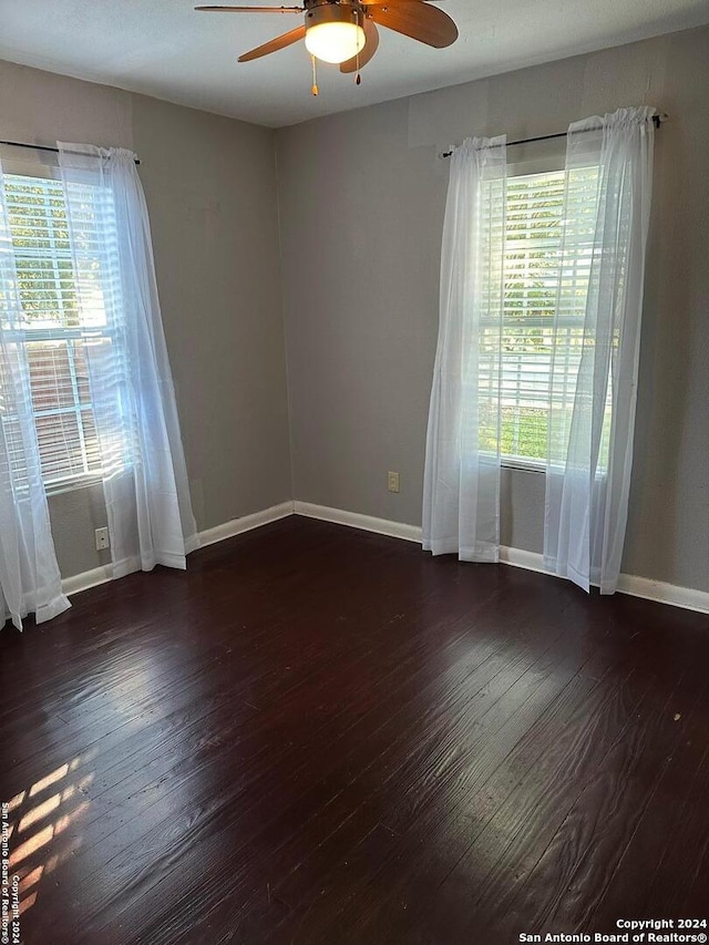 empty room with ceiling fan and dark hardwood / wood-style flooring