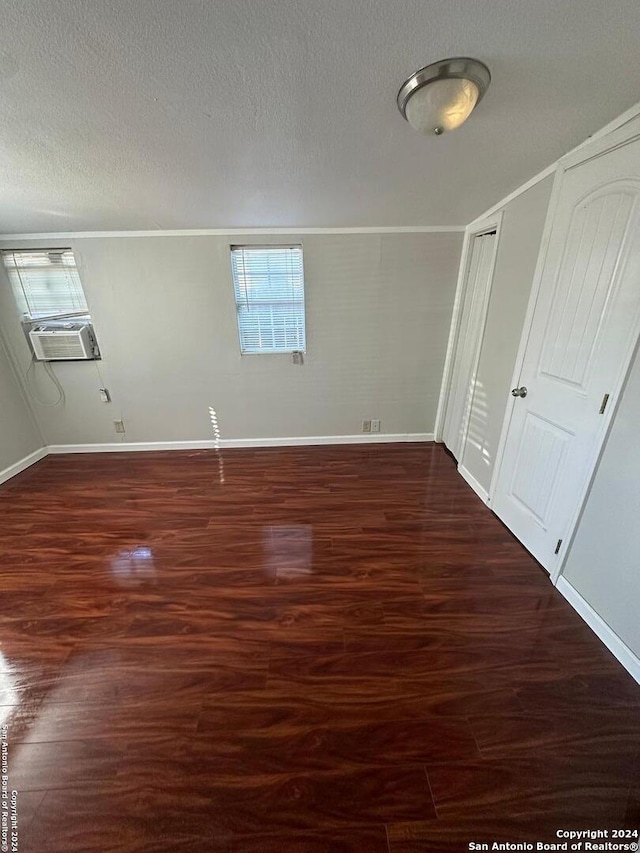 unfurnished room with cooling unit, dark wood-type flooring, and a textured ceiling