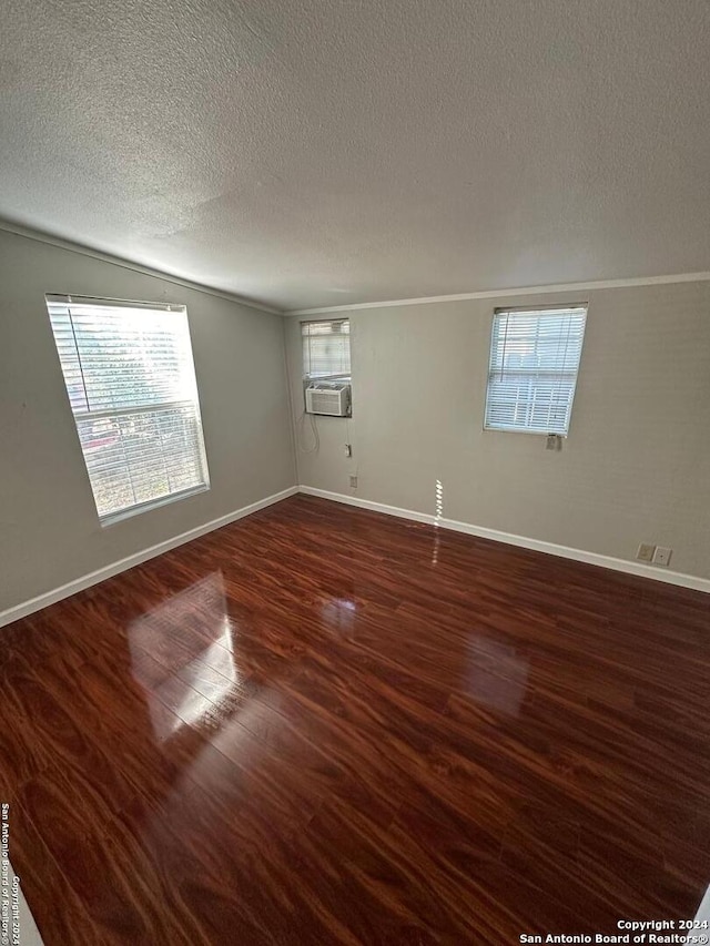 empty room with a textured ceiling, a wealth of natural light, cooling unit, and dark hardwood / wood-style floors