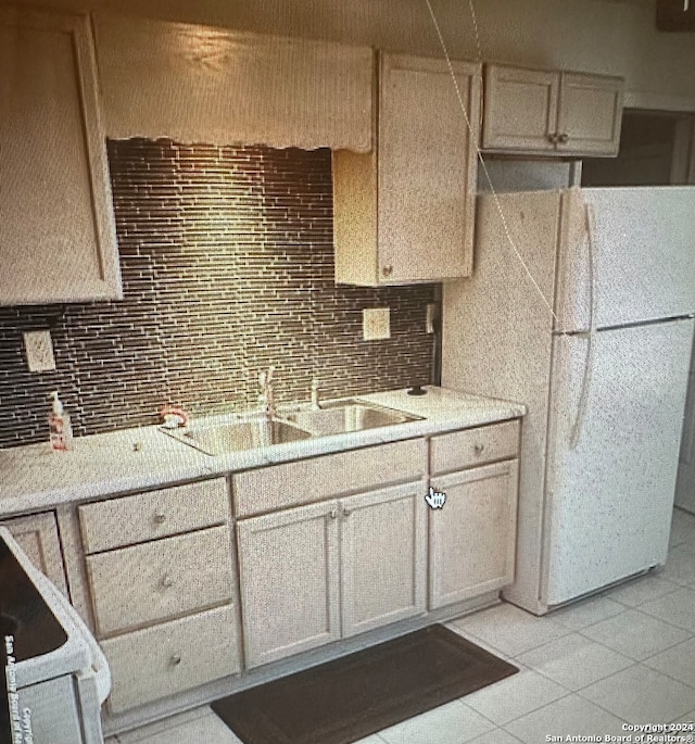 kitchen featuring decorative backsplash, light tile patterned floors, white fridge, and sink