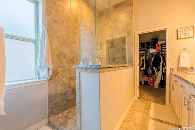 bathroom with tiled shower and vanity