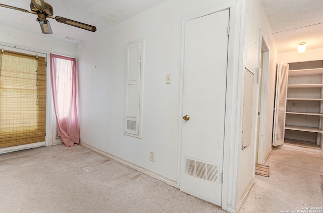 unfurnished bedroom featuring ceiling fan, light colored carpet, and a textured ceiling