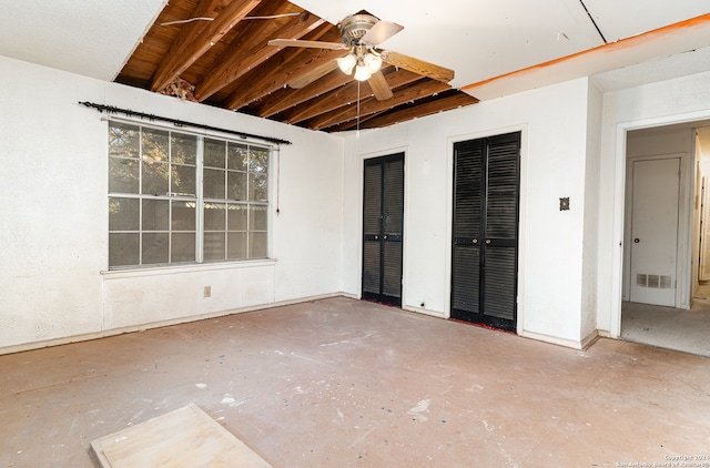 unfurnished bedroom with ceiling fan and two closets